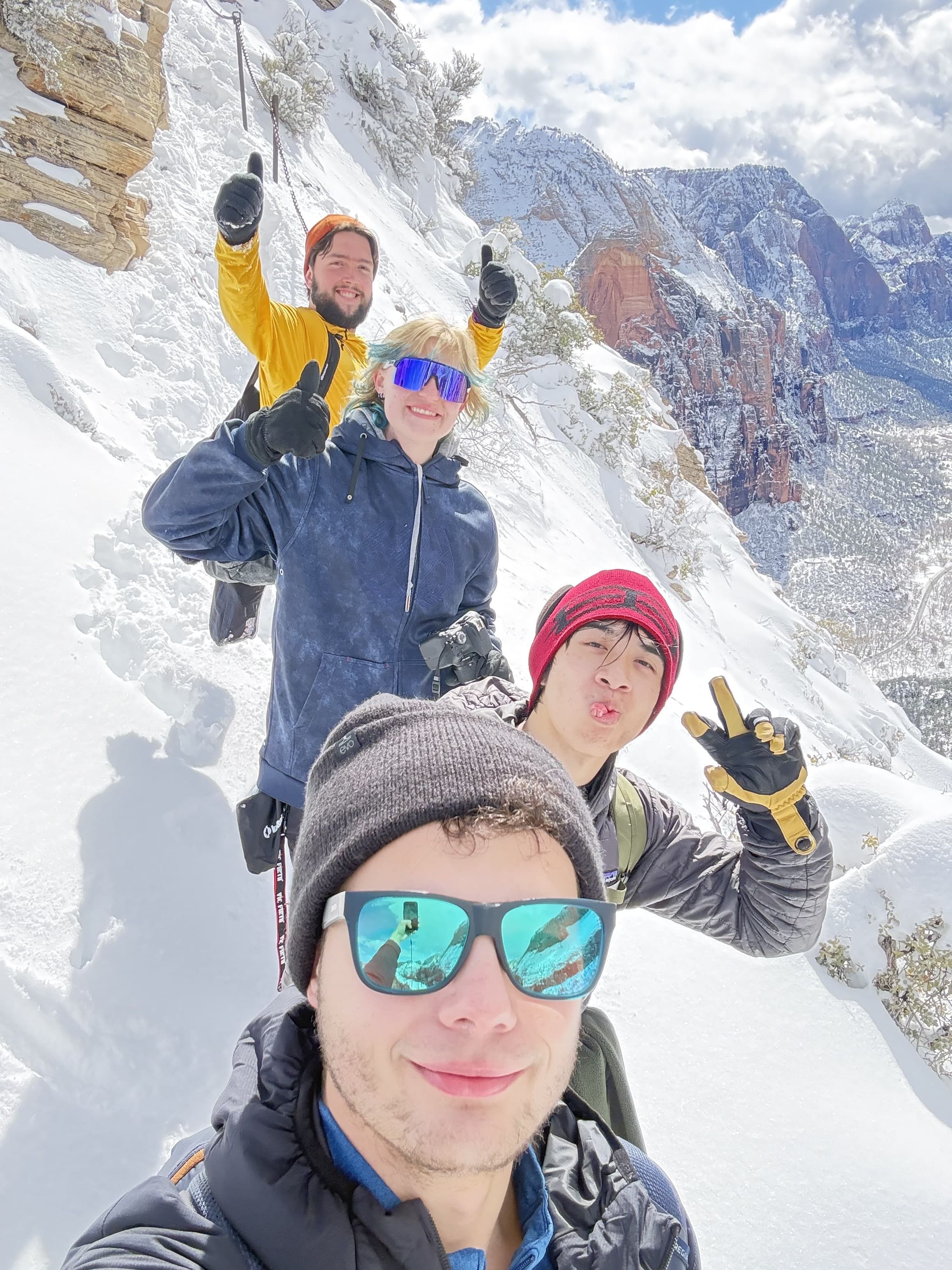 Club members in winter gear pose for a selfie on a snowy mountain slope.