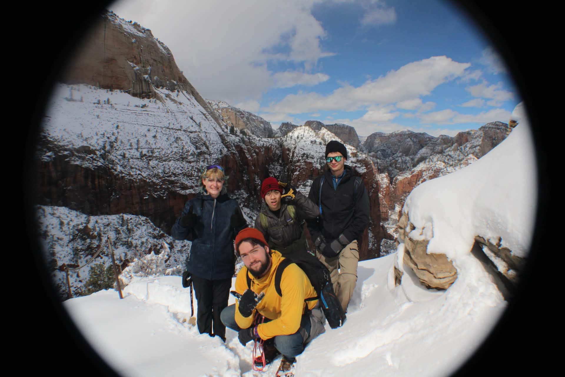Club members in colorful winter jackets pose together in deep snow near a rocky ridge.